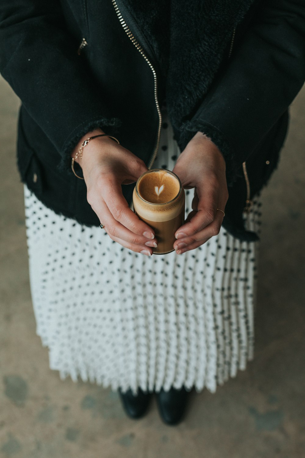 woman holding glass with brown liquid