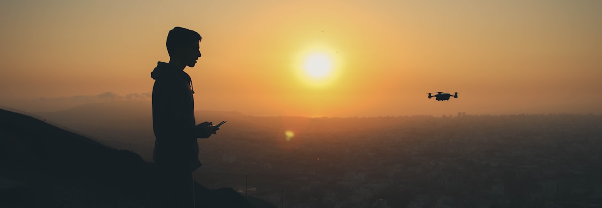 a man holding drone remote control while drone in the air