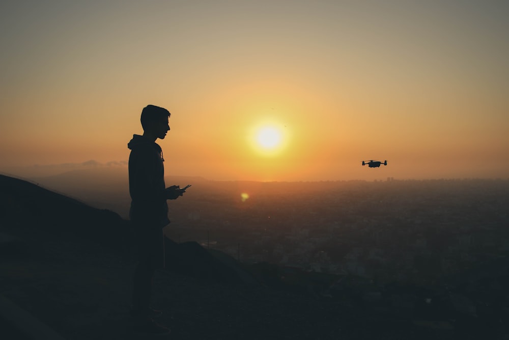 foto silhouette di uomo che tiene il telecomando del drone