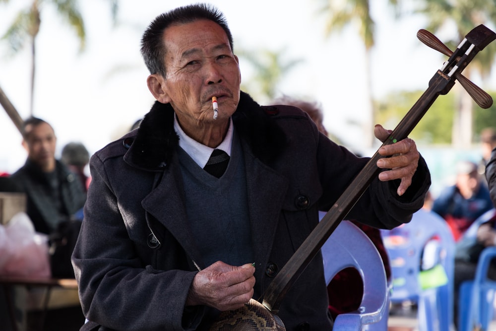 man wearing black suit holding guitar while smoking