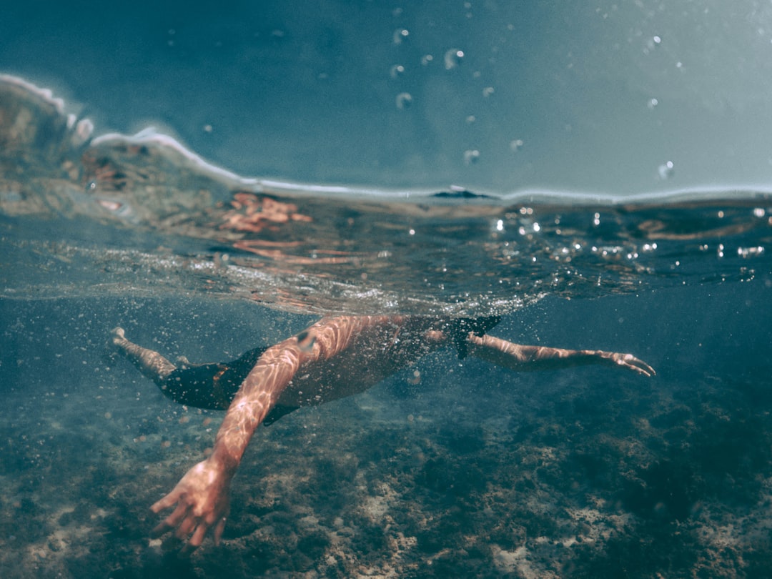 man in black shorts swimming on body of water