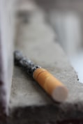 selective focus photography of red cigarette butt on grey surface