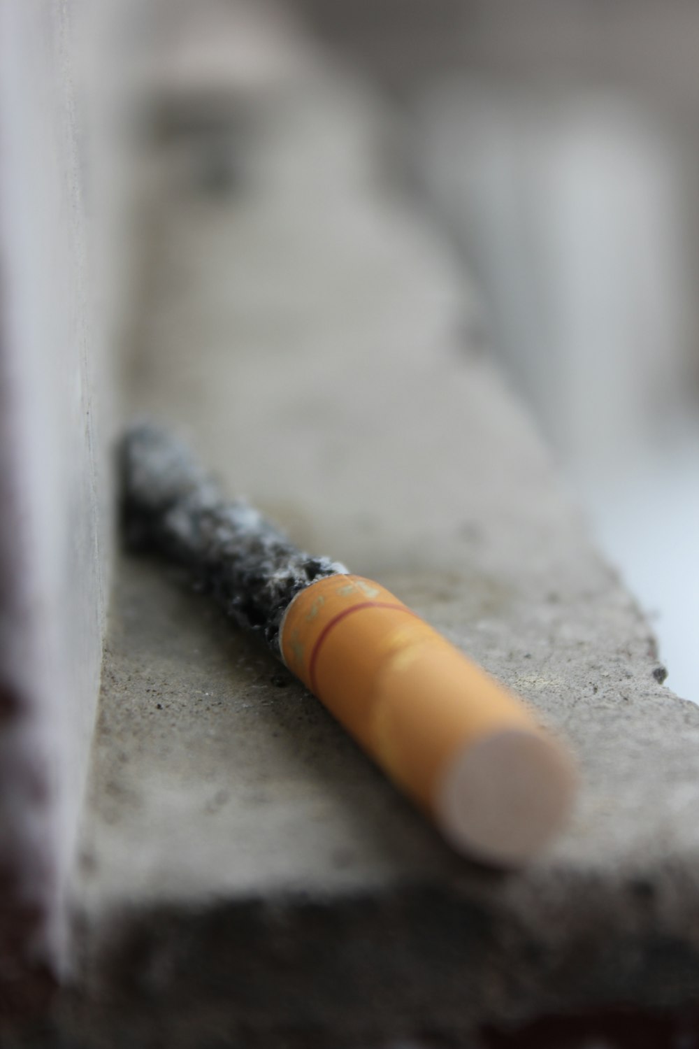 Fotografía de enfoque selectivo de colilla de cigarrillo roja sobre superficie gris