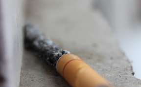 selective focus photography of red cigarette butt on grey surface