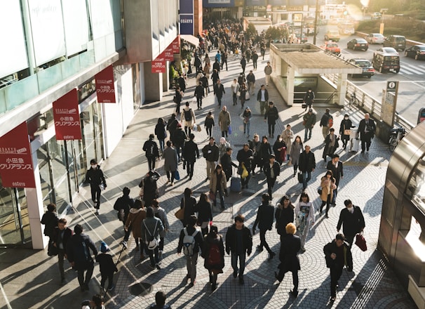 aerial photography of people walking on sidewalk near building during daytime