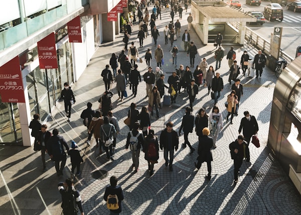 aerial photography of people walking on sidewalk near building during daytime