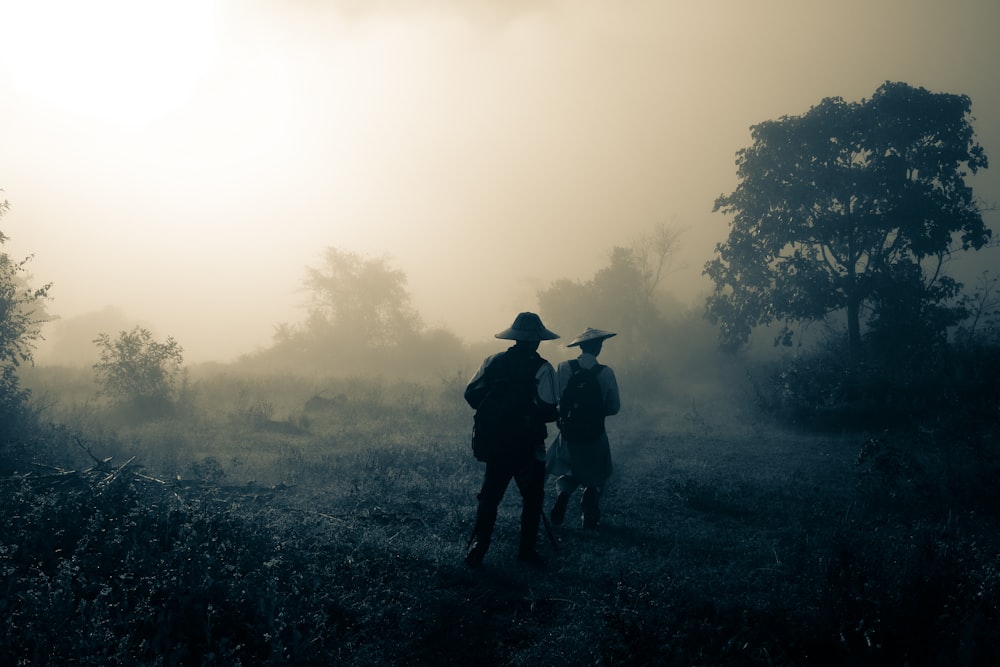 two men walking on forest covered with fog