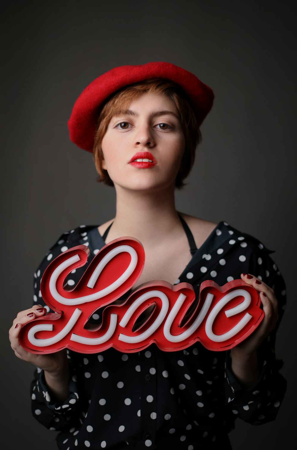 woman wearing black and white polka-dot top holding love freestanding letter