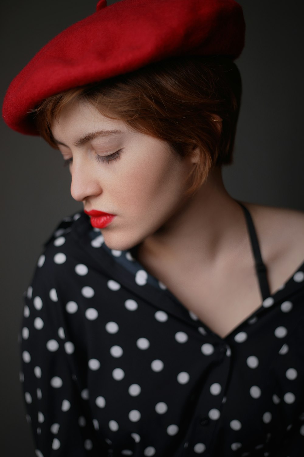 Mujer con sombrero rojo de vendedor de periódicos y blusa abotonada con lunares blancos y negros