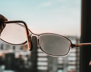 Hands holding a pair of talking eyes eyeglasses against a soft, blurred cityscape
