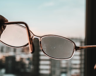 An artistic shot of classic round spectacles with a blurred city background.