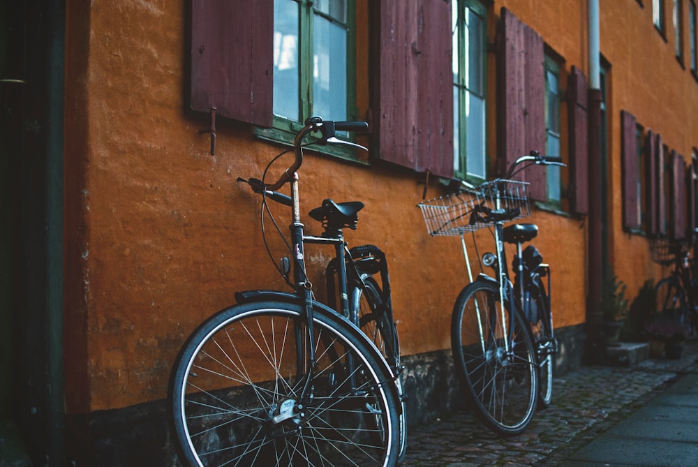 two black city bikes on brown concrete wall