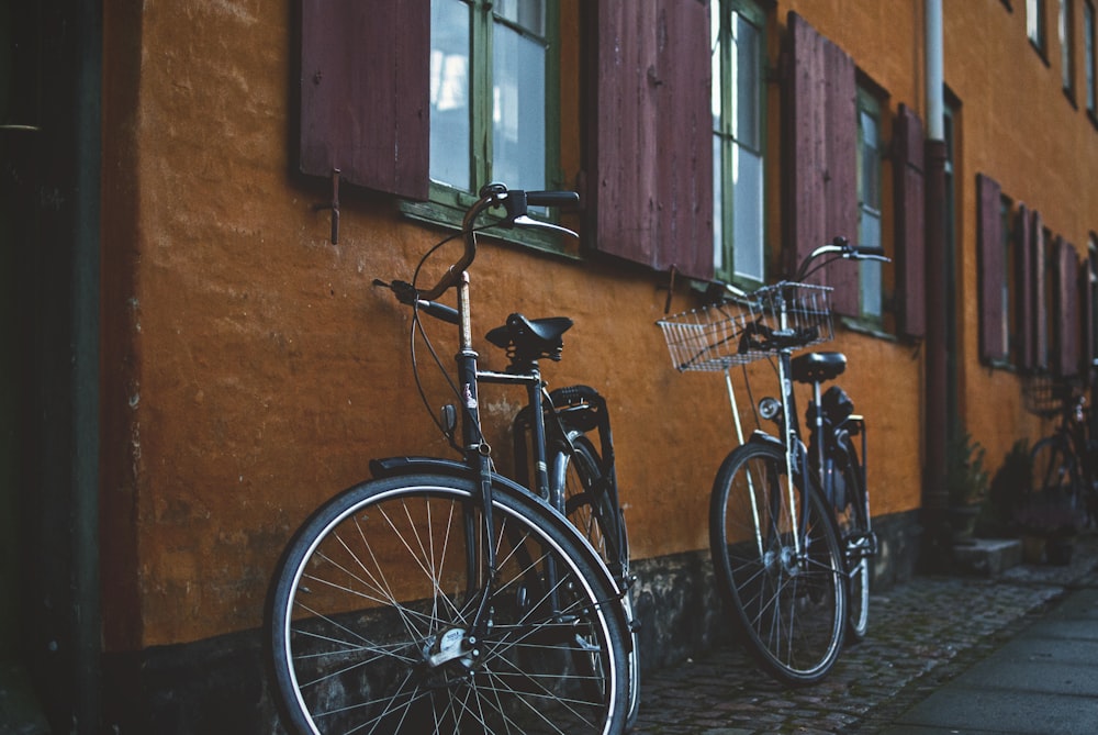 two black city bikes on brown concrete wall