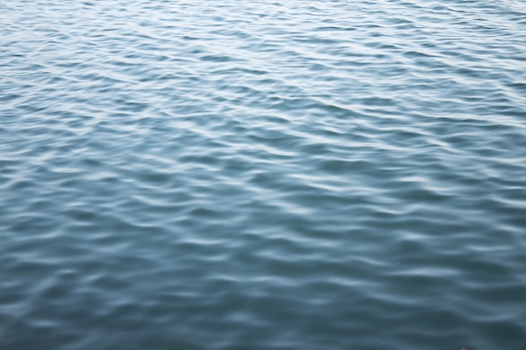 A serene body of water with gentle ripples creating a textured pattern across the surface. The calm appearance suggests a peaceful environment.