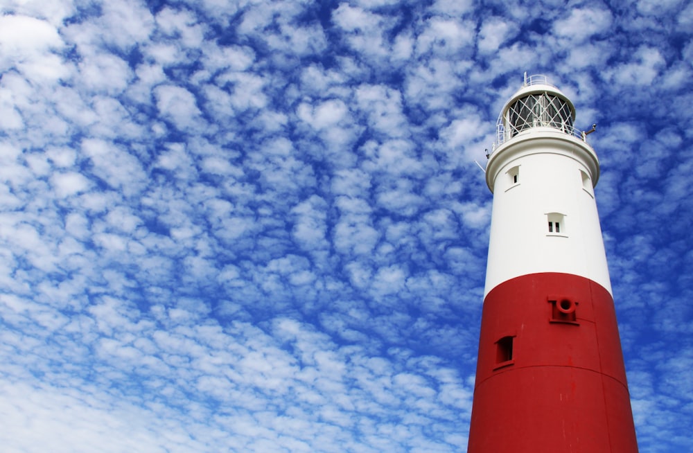 farol branco e vermelho sob céu nublado