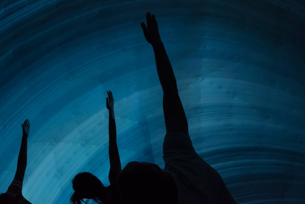 two people reaching up into a blue ice cave