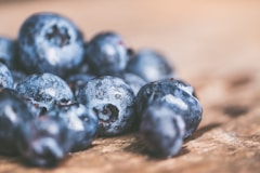 A close-up of fresh, plump wild blueberries on a wooden table.