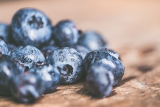 Close-up of fresh mixed berries glistening with morning dew on a rustic wooden table.