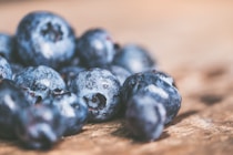 Close-up of fresh, vibrant berries glistening with morning dew on a rustic wooden table