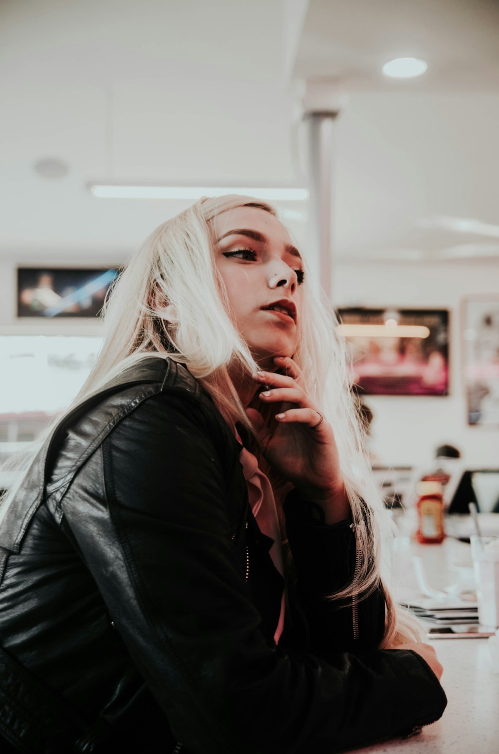 woman wearing black leather jacket sitting down near table