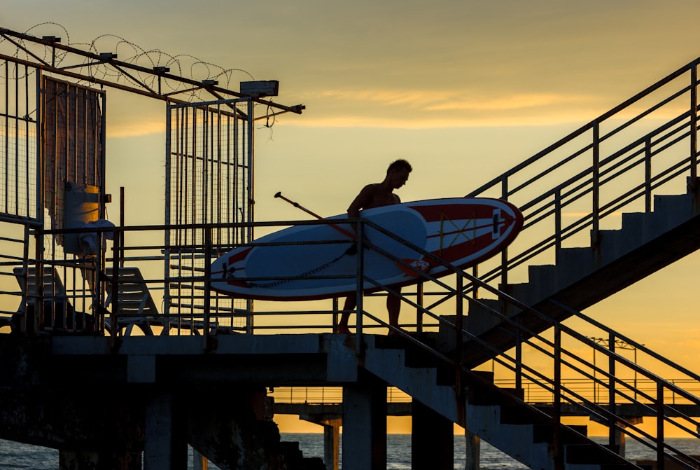 man holding paddle board during golden hour