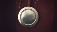 A silver metallic plate is attached to a dark brown surface, possibly a wooden door or wall. The plate is slightly tarnished, adding a rustic feel to the setting.