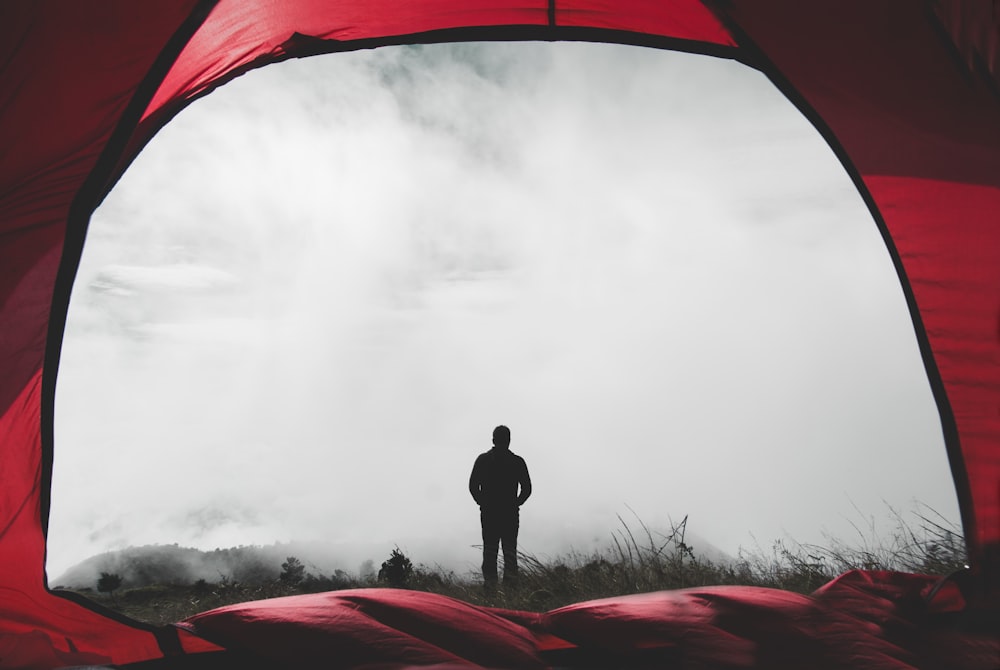 man standing on grass field during misty day