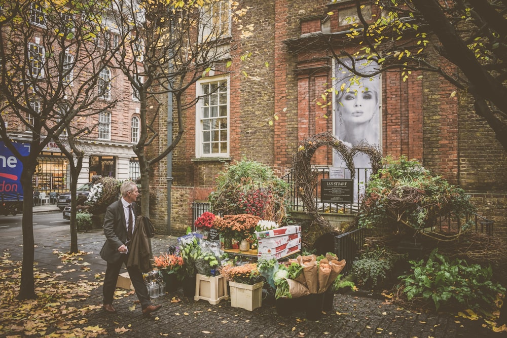 man walking beside flowershop