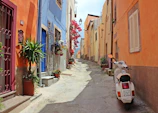 A charming narrow street in Siracusa lined with colorful buildings and blooming flowers.