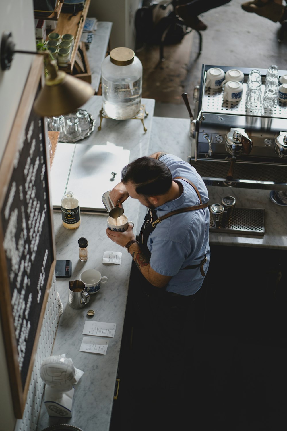 man wearing blue shirt pouring coffee in his cup