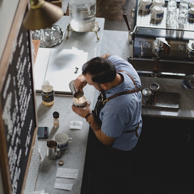 man wearing blue shirt pouring coffee in his cup