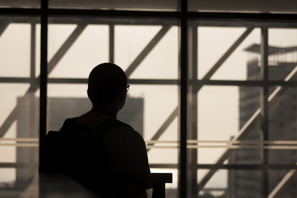 silhouette photo of man wearing eyeglasses sitting on chair