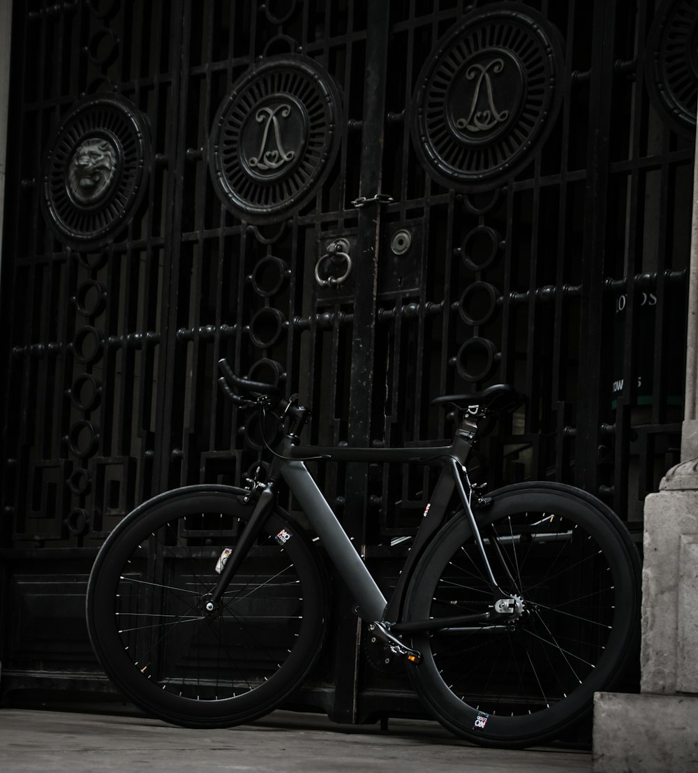 black fixed-gear bike leaning on black steel gate