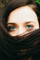 portrait photography of woman covering her face with hair