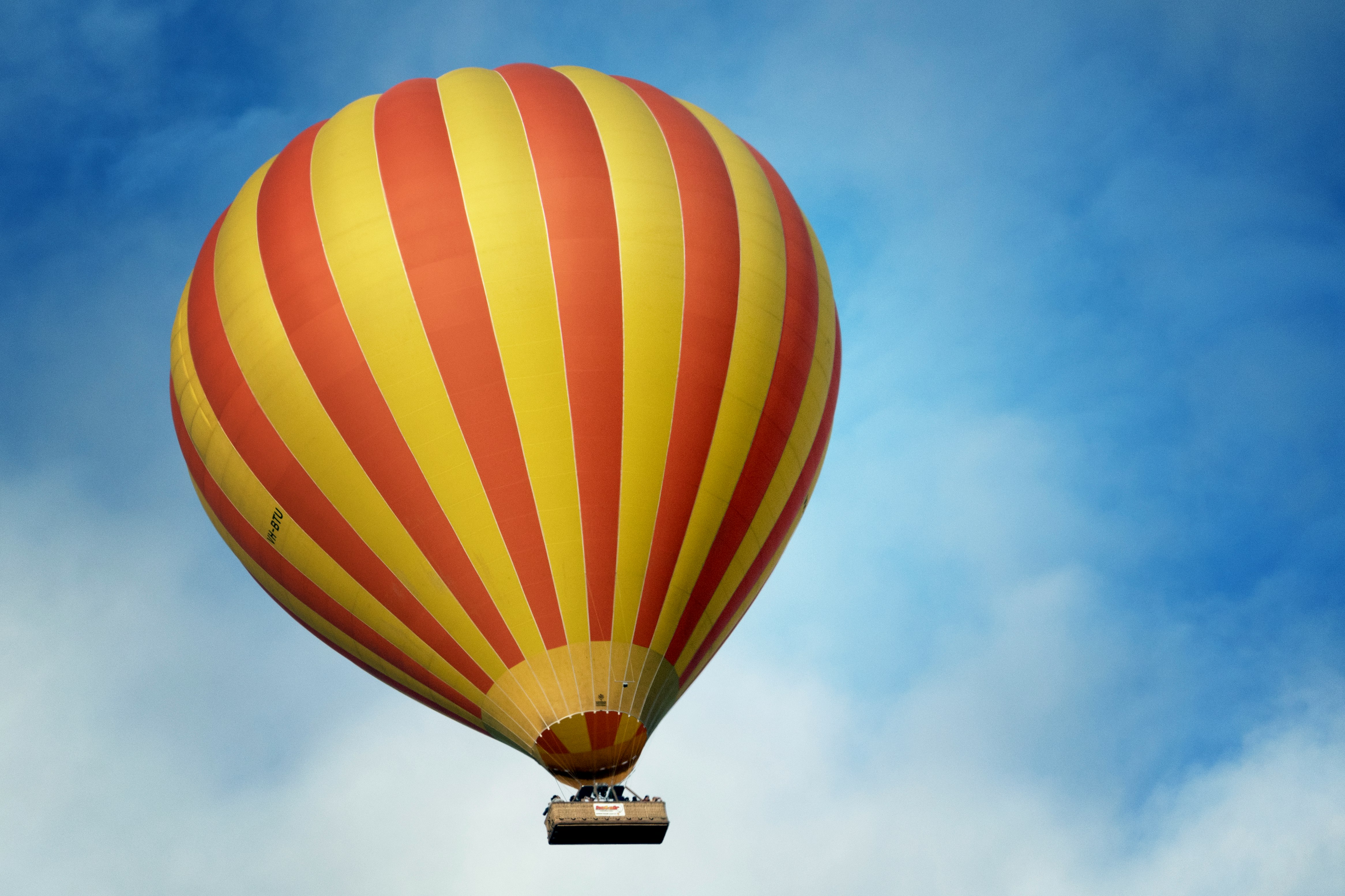 low angle photography of yellow and red stripe hot air balloon