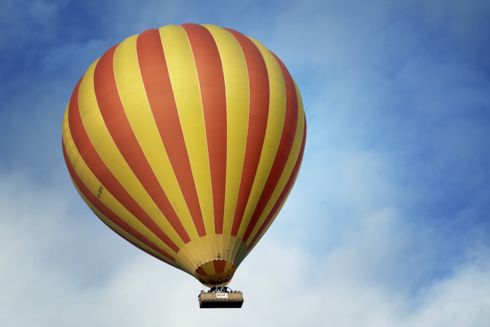 low angle photography of yellow and red stripe hot air balloon