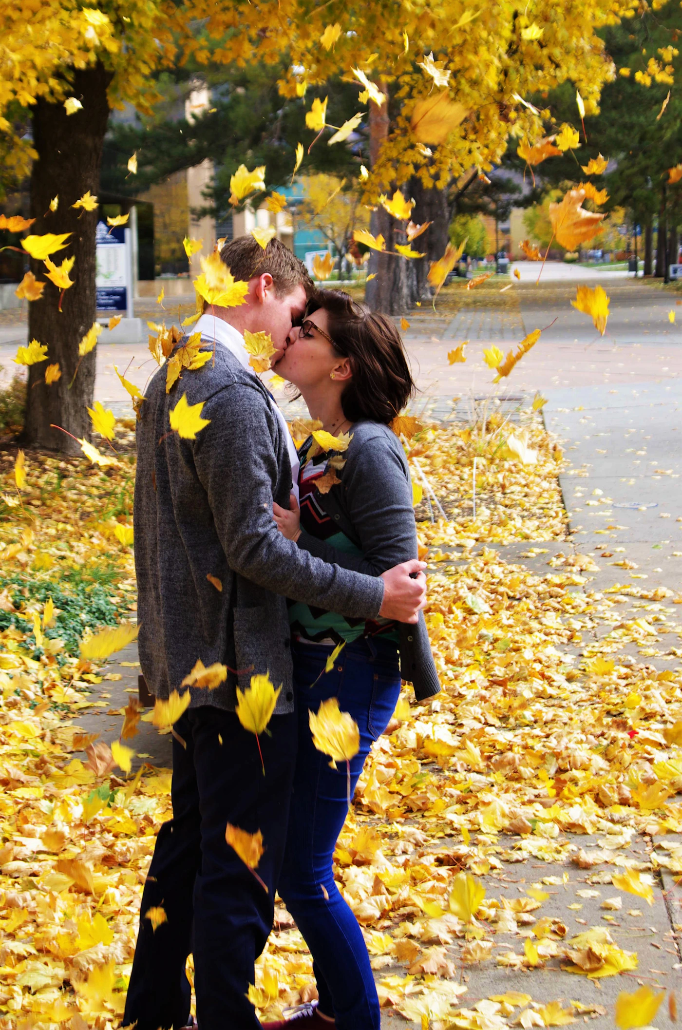 Couple sharing a tender romantic kiss surrounded by the warm golden tones of autumn fall leaves and foliage