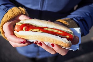 person holding hotdog with bun
