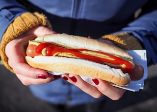 person holding hotdog with bun