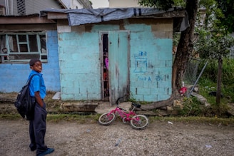 um menino pobre em frente sua casa velha.