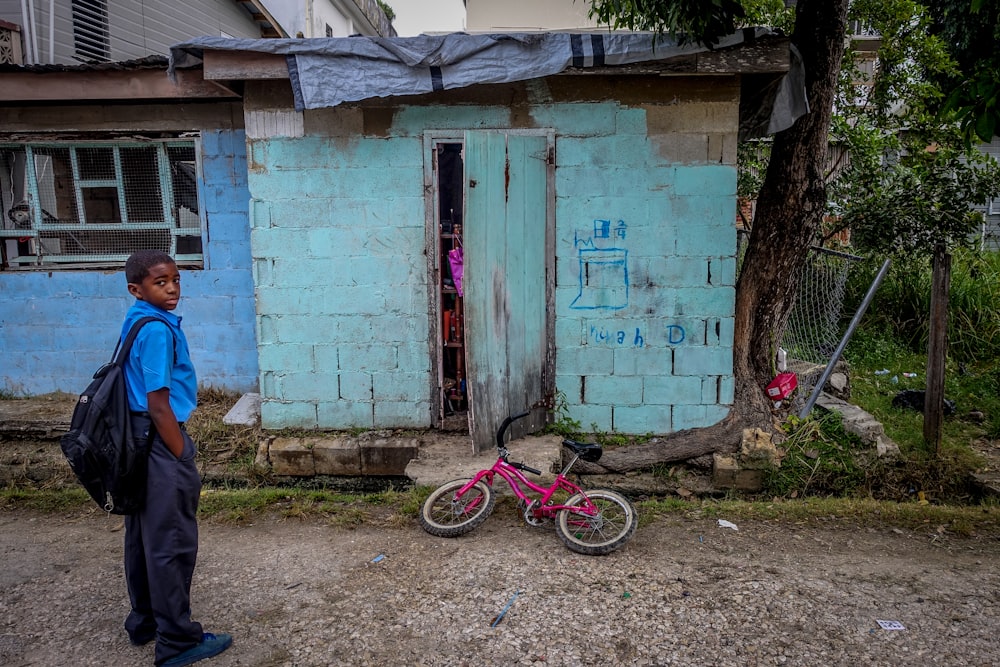 Junge steht vor Tür in der Nähe eines Fahrrads