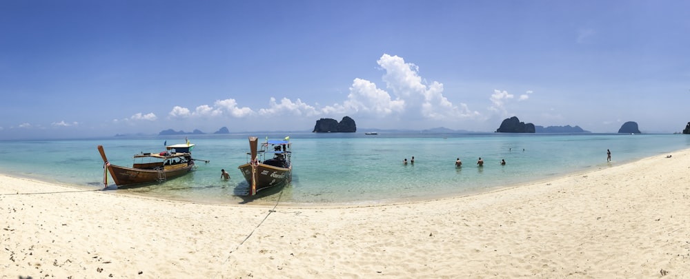 people on beach beside two brown boats during daytime