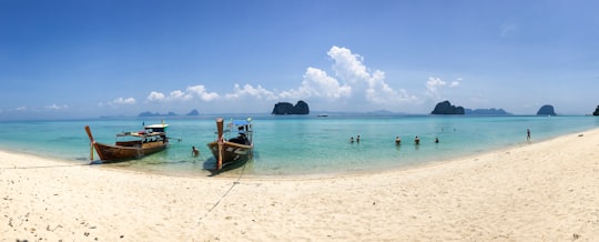 people on beach beside two brown boats during daytime in Ko Lanta Thailand