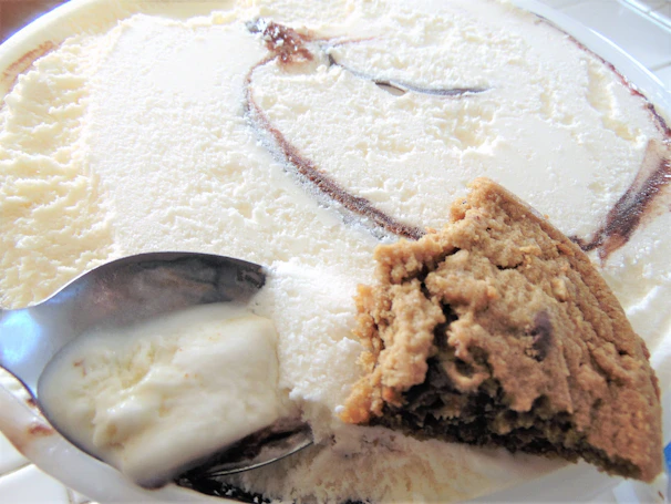 A creamy swirl of homemade vanilla ice cream being scooped from a chilled metal container.