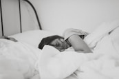 grayscale photo of sleeping woman lying on bed