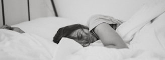 grayscale photo of sleeping woman lying on bed