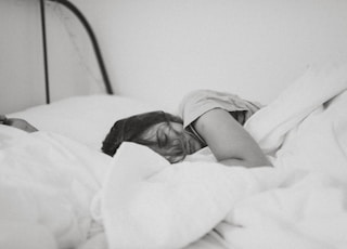 grayscale photo of sleeping woman lying on bed