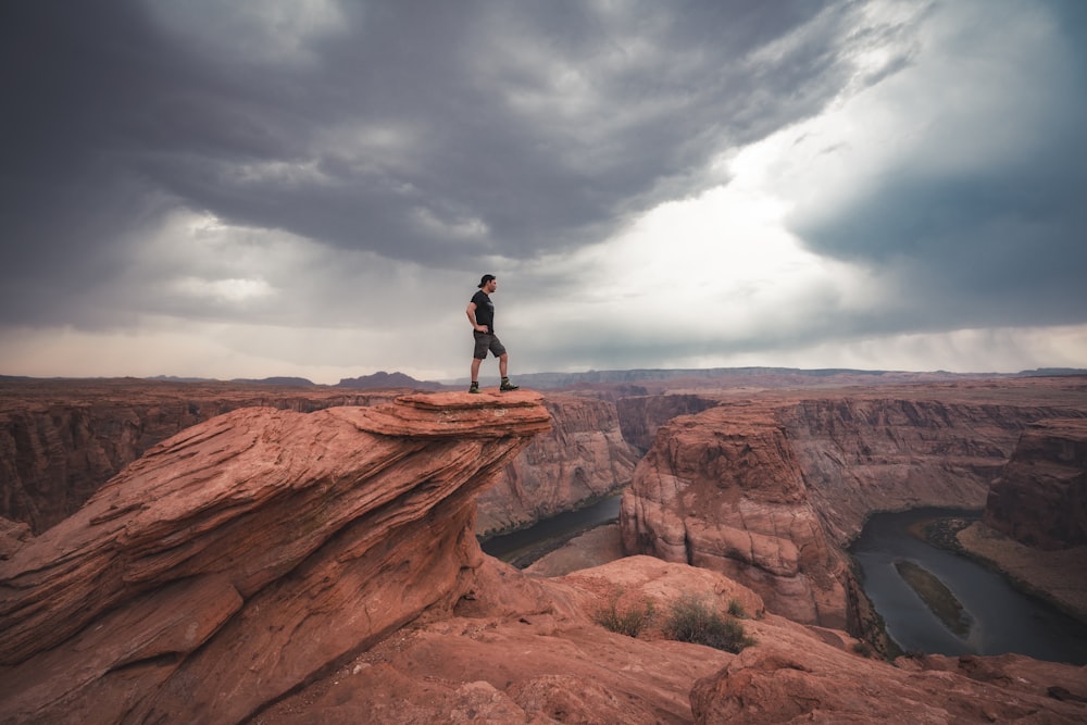 man standing on top of horseshoe bend at Arizona
