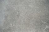 A textured grey concrete surface with visible scratches and variations in shading.