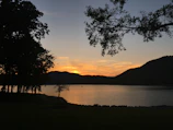 A peaceful lakeside spot reflecting the surrounding hills at sunset.